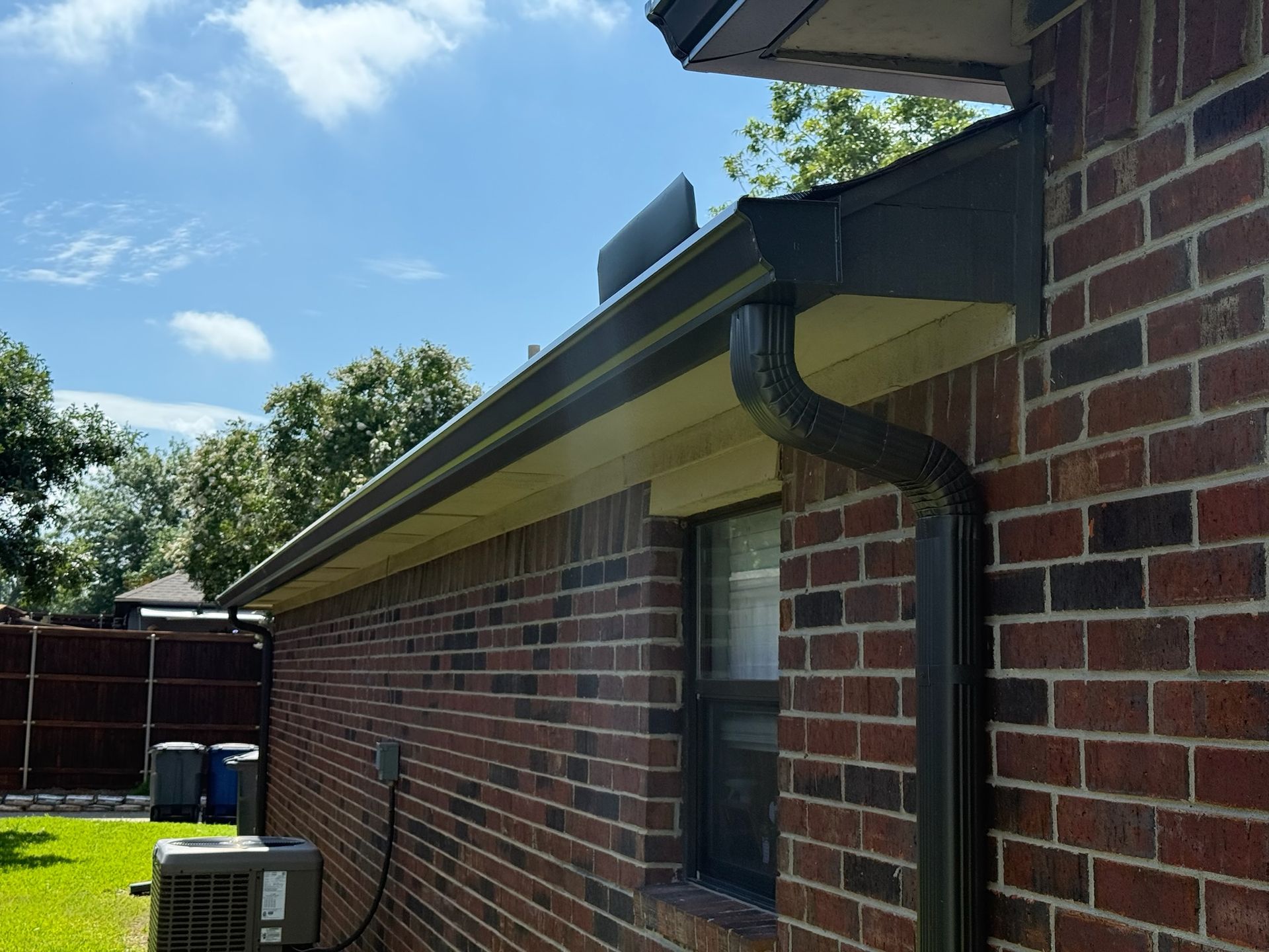 A brick house with a black gutter and a window.
