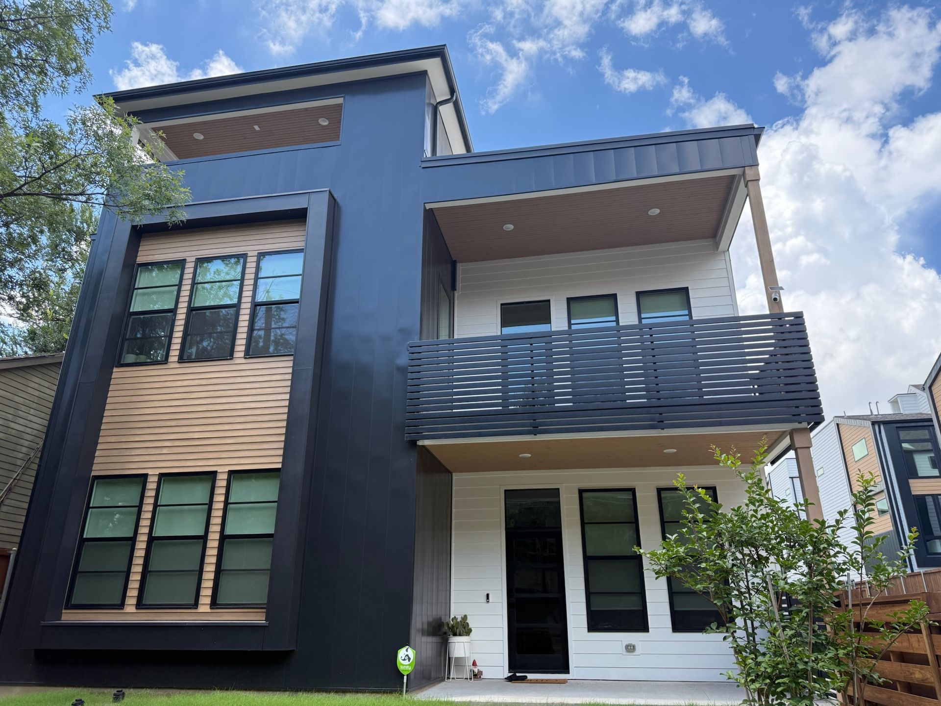 A black and white house with a balcony and a blue sky in the background.