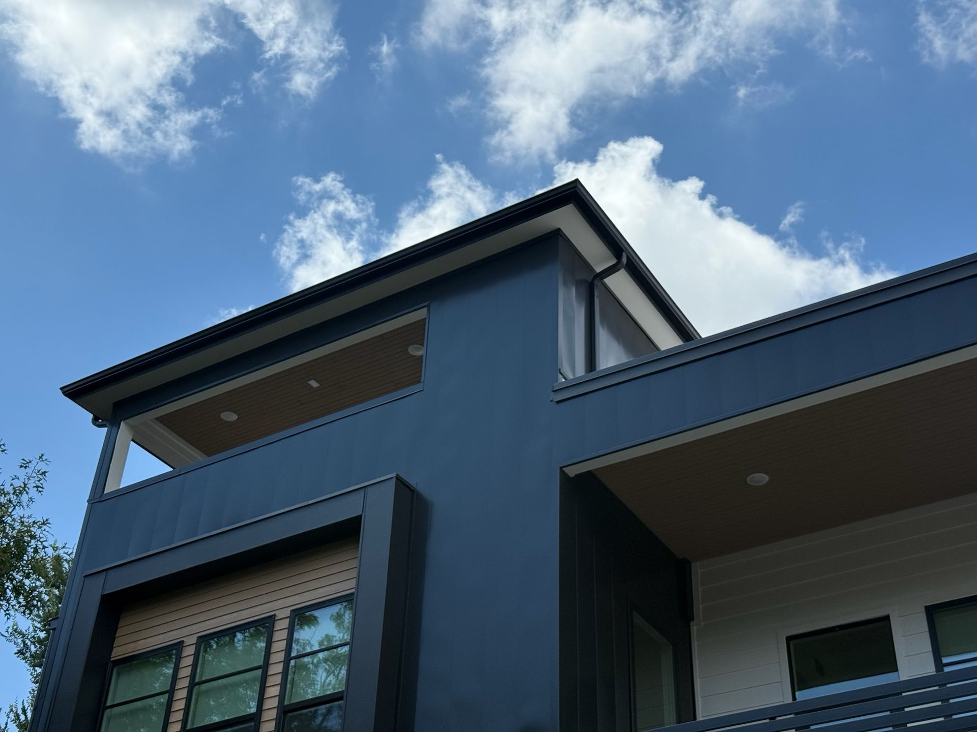 A large house with a balcony and a blue sky in the background.