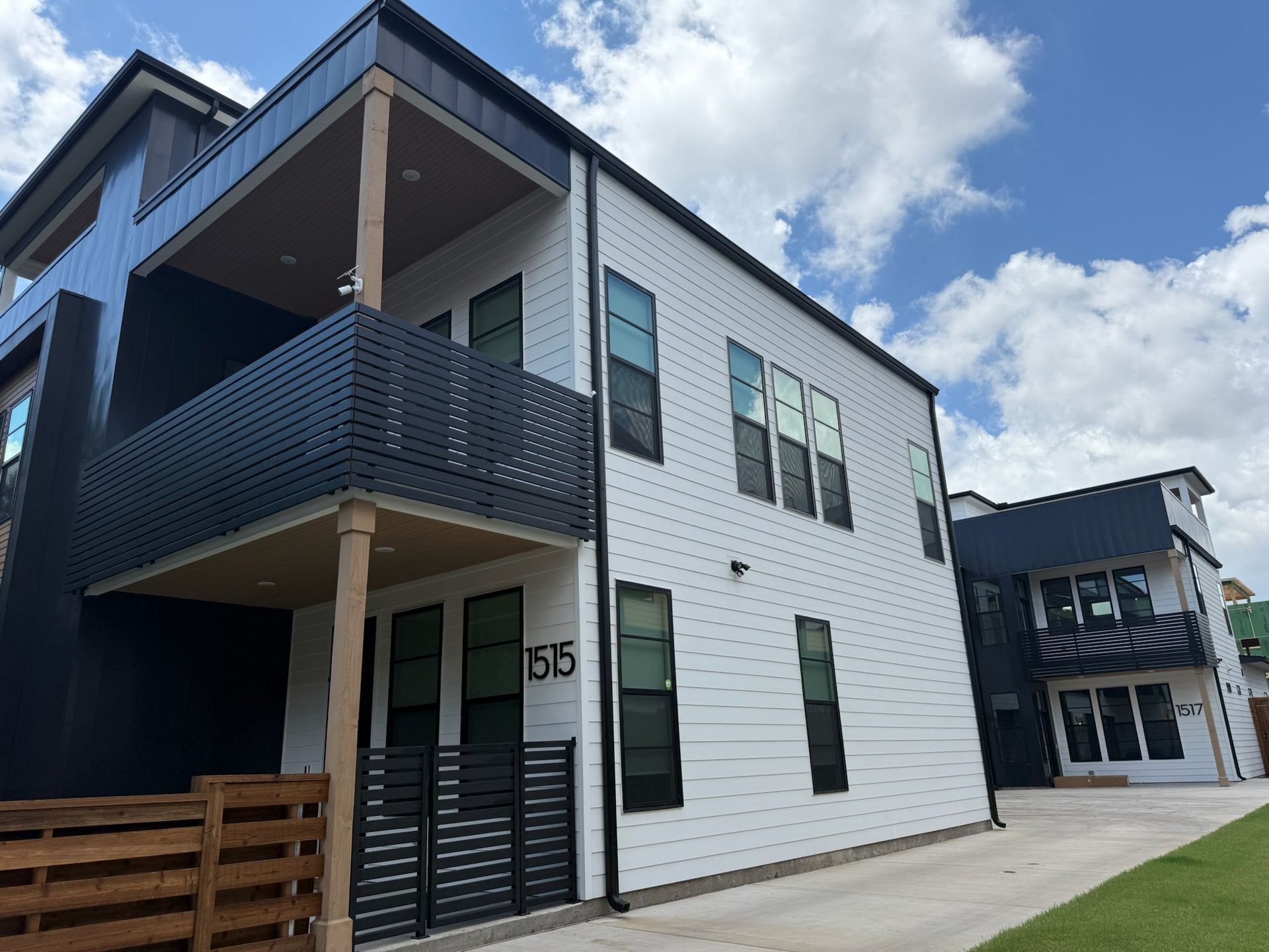 A white and black apartment building with a wooden fence in front of it.