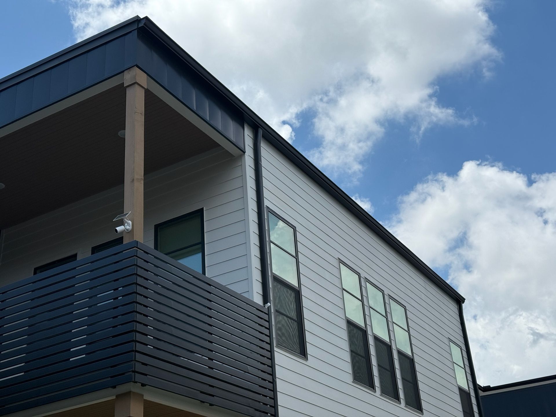 A house with a balcony and a blue sky in the background