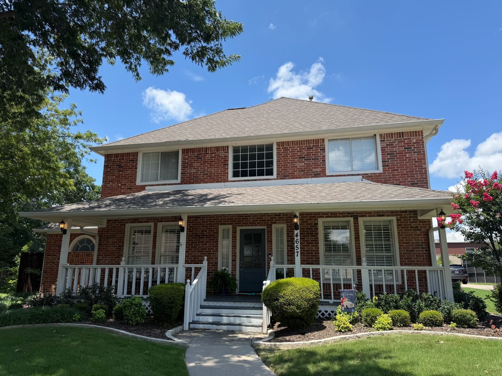 A large brick house with a porch and a blue door