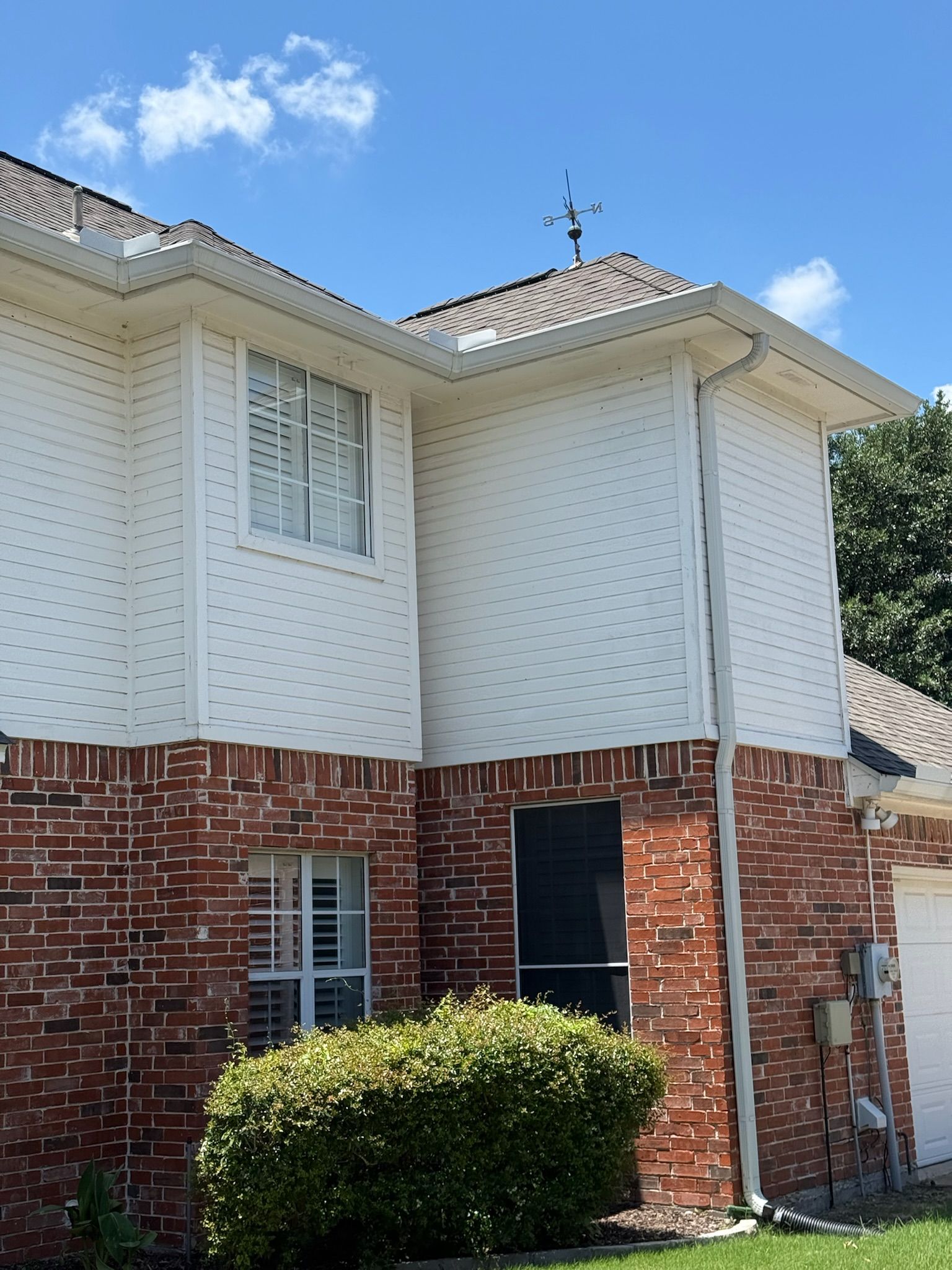 A brick house with white siding and a garage