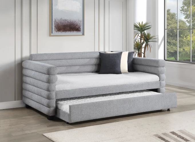 A grey day bed with a pull out bed underneath it in a living room.
