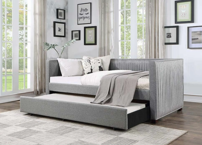 A day bed with a pull out bed underneath it in a bedroom.