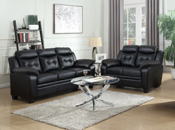 A living room with two black leather couches and a coffee table.