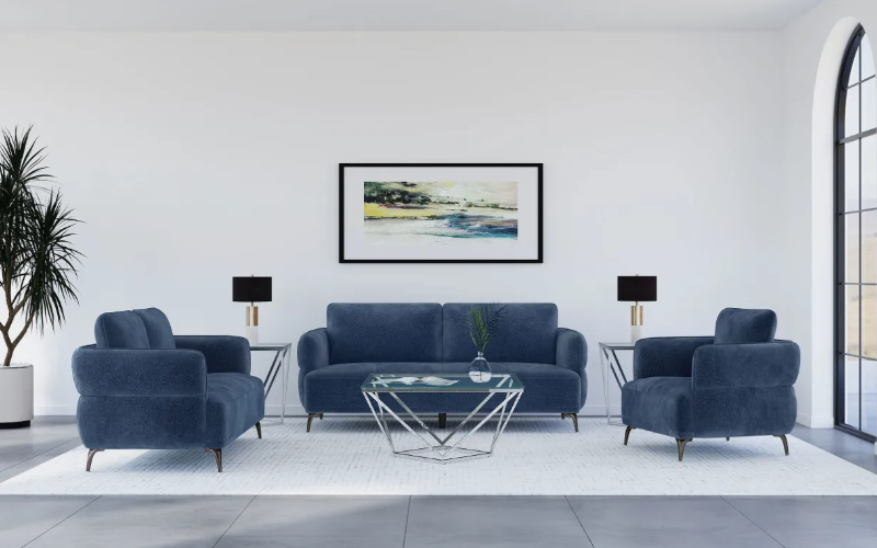A living room with a blue couch , two chairs , a coffee table and a picture on the wall.
