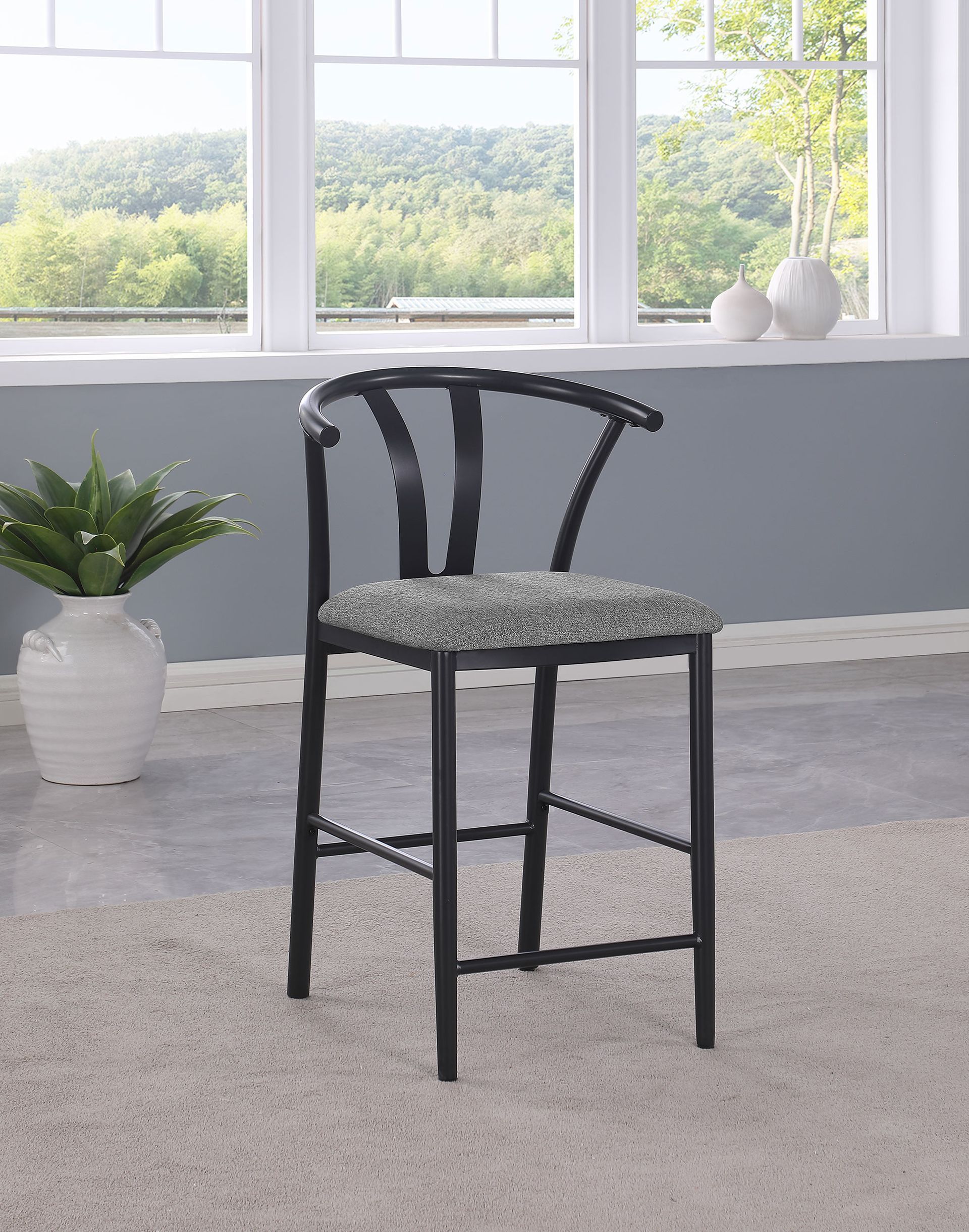 A black bar stool is sitting in front of a window in a living room.