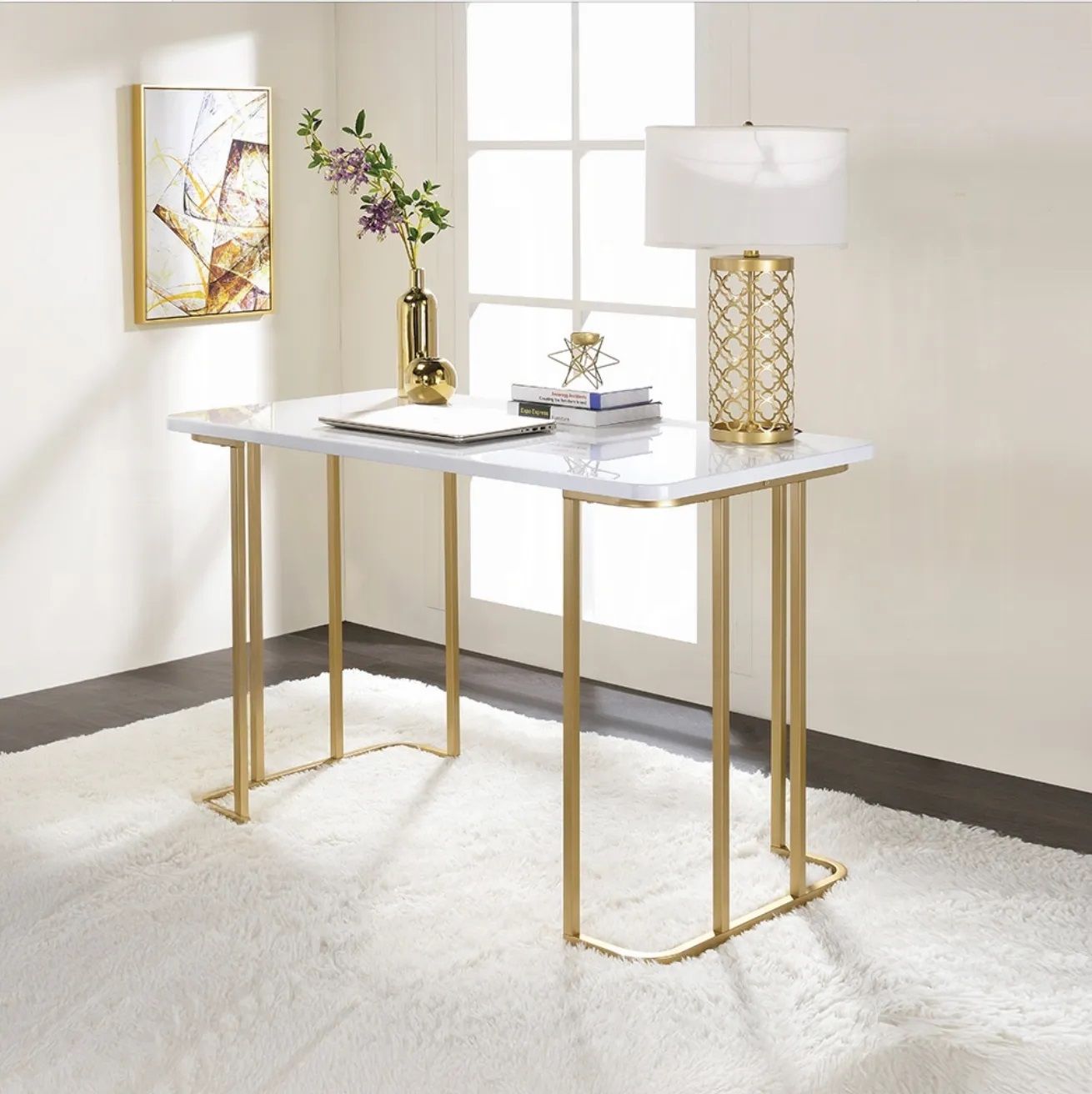 A white desk with gold legs is in a room next to a window.