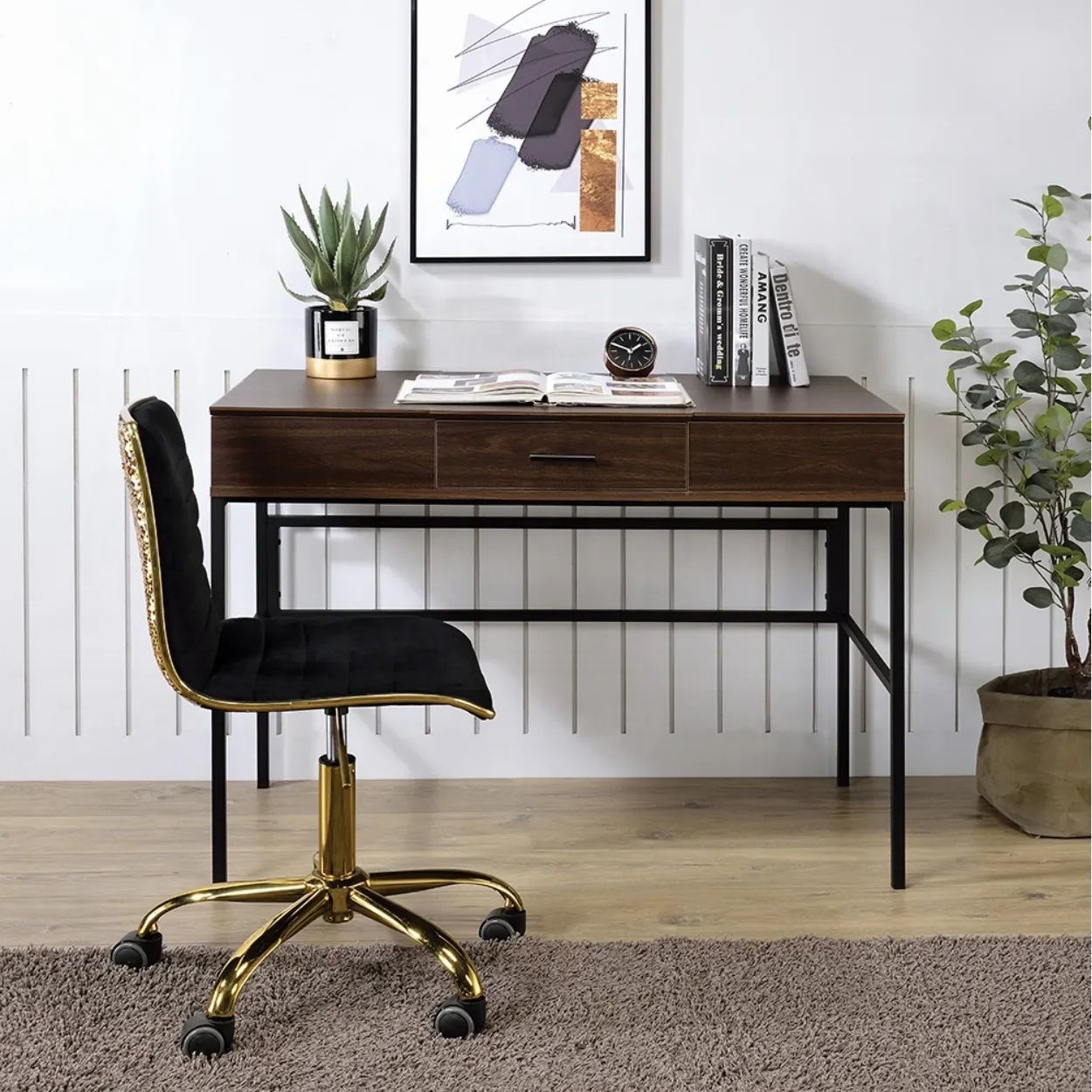 A desk with a chair and a picture on the wall above it.