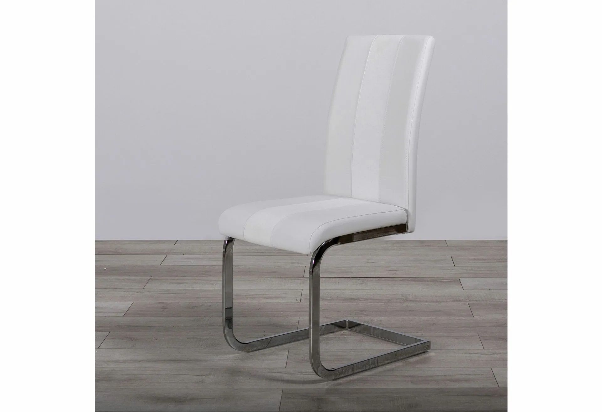 A white dining chair with a chrome frame is sitting on a wooden floor.