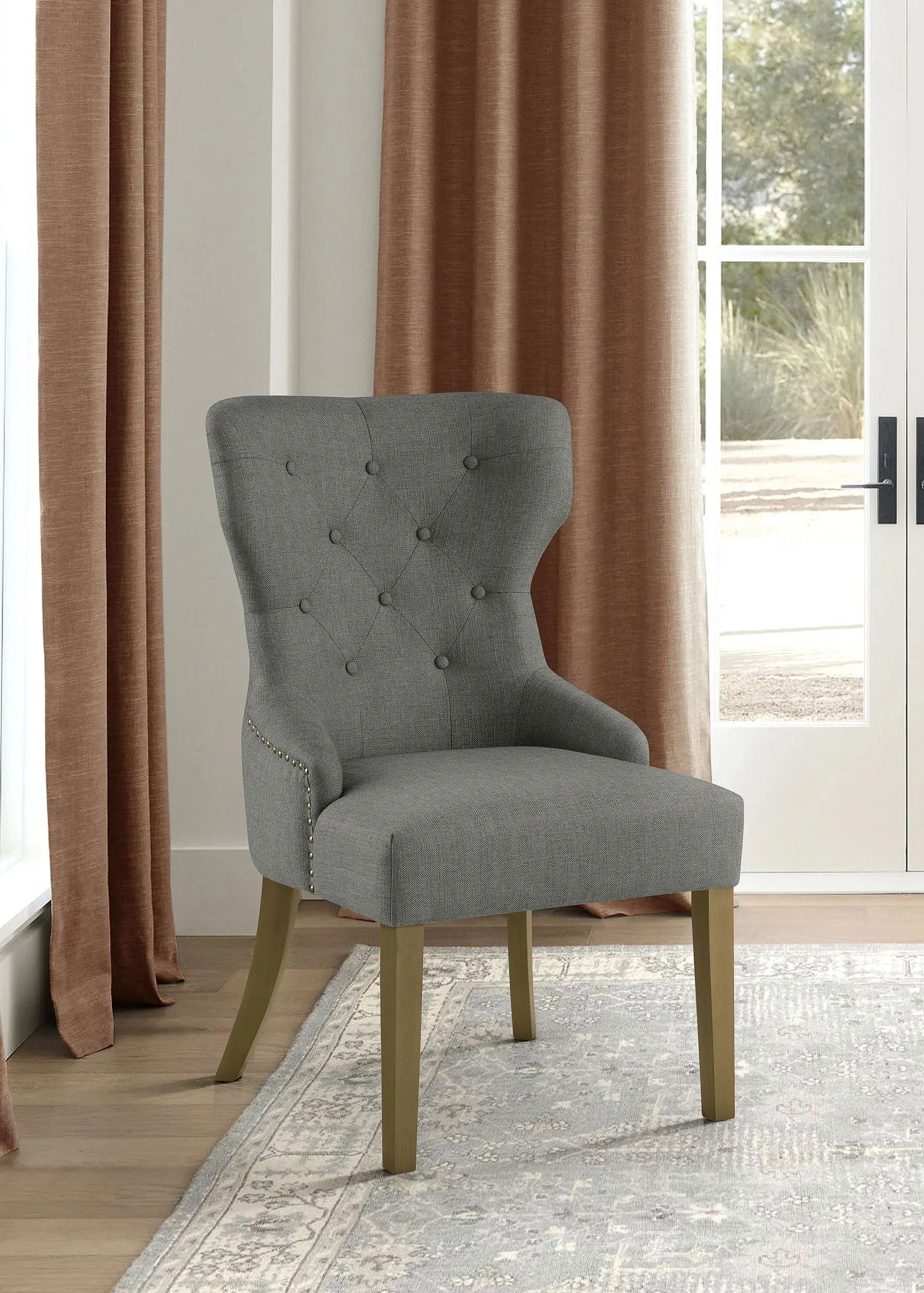 A gray chair is sitting in a living room next to a window.