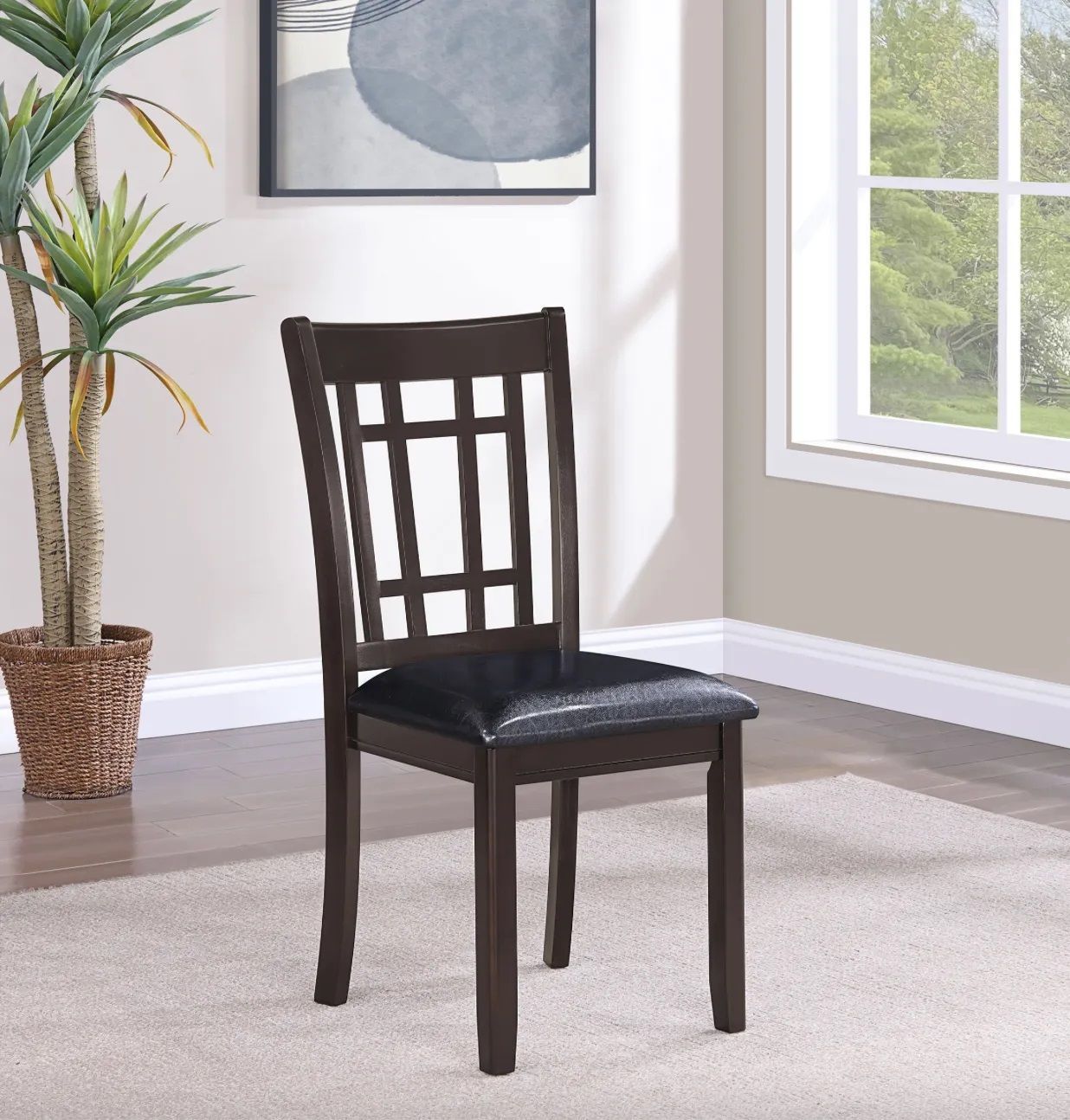 A chair in a living room next to a plant and a window