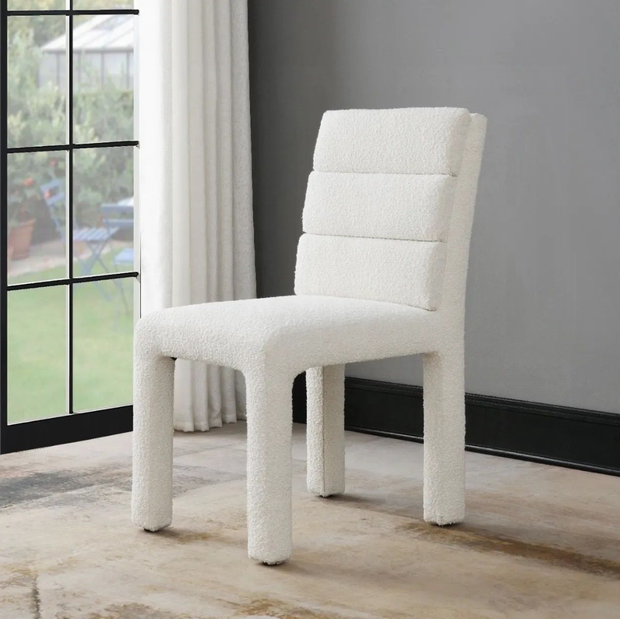 A white chair is sitting in front of a window in a room.