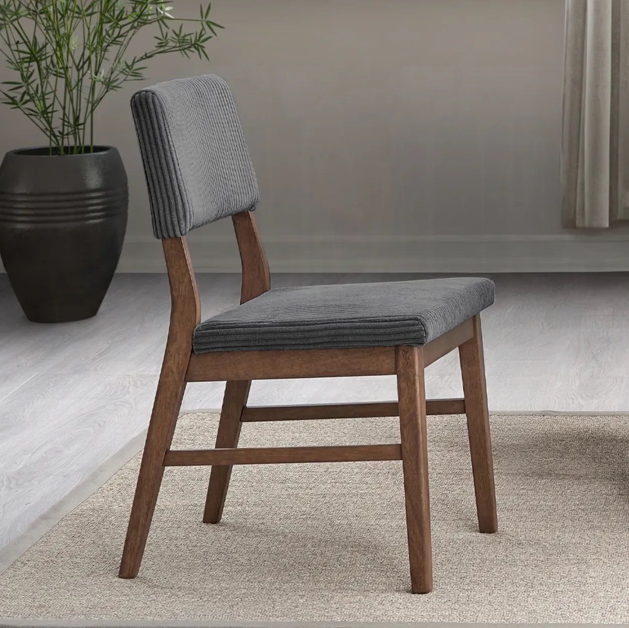 A chair is sitting on a rug next to a potted plant