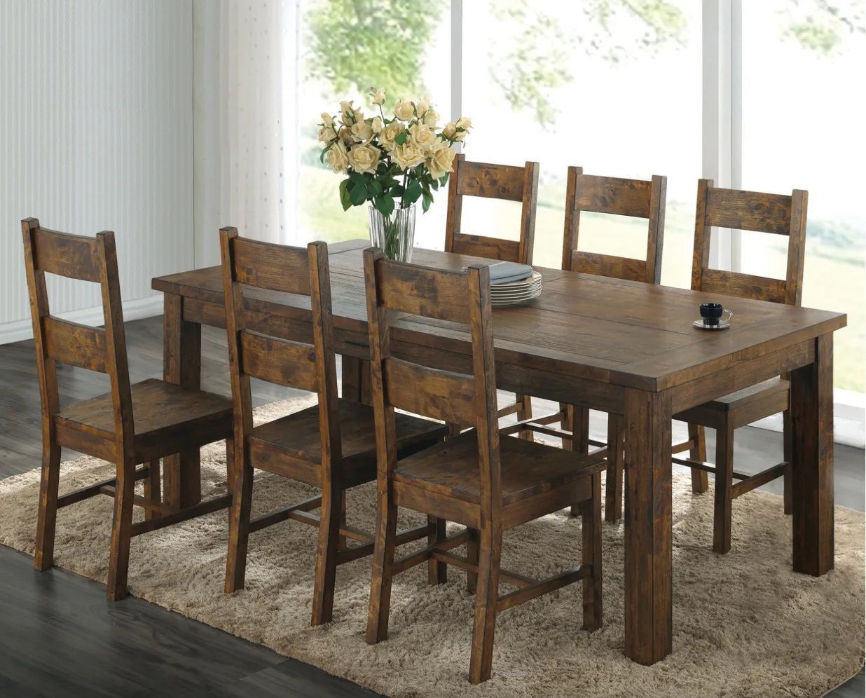 A wooden dining table and chairs in a room with a vase of flowers on it.