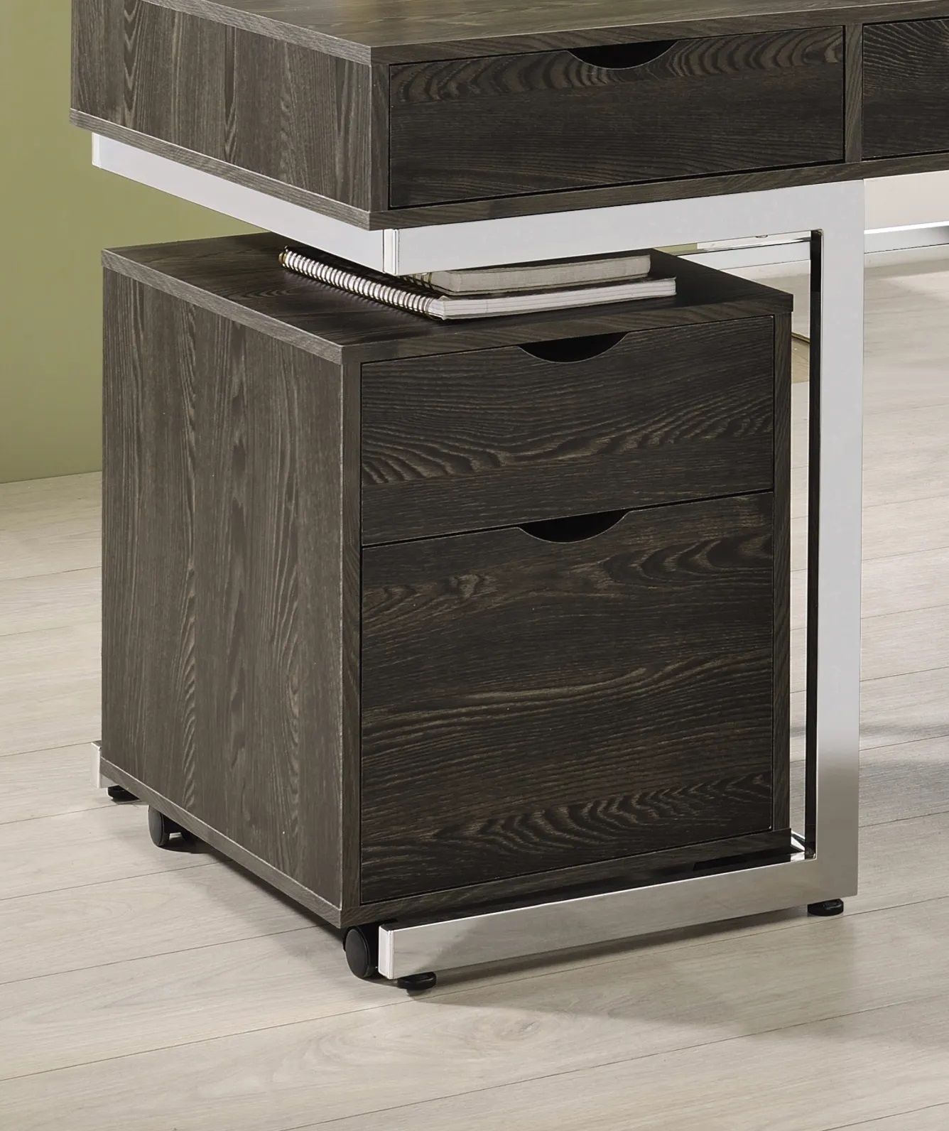 A wooden filing cabinet is sitting under a desk.