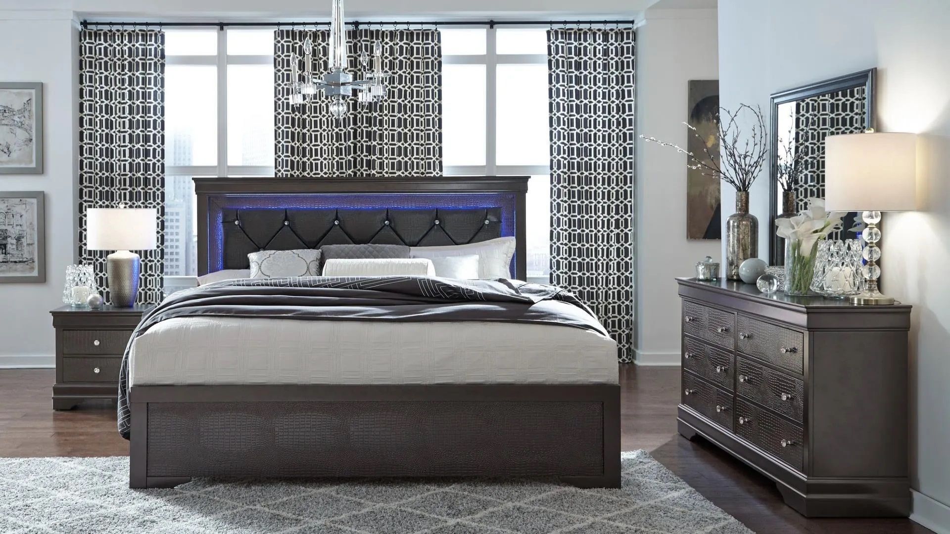 A bedroom with a bed , dresser , nightstand and mirror.