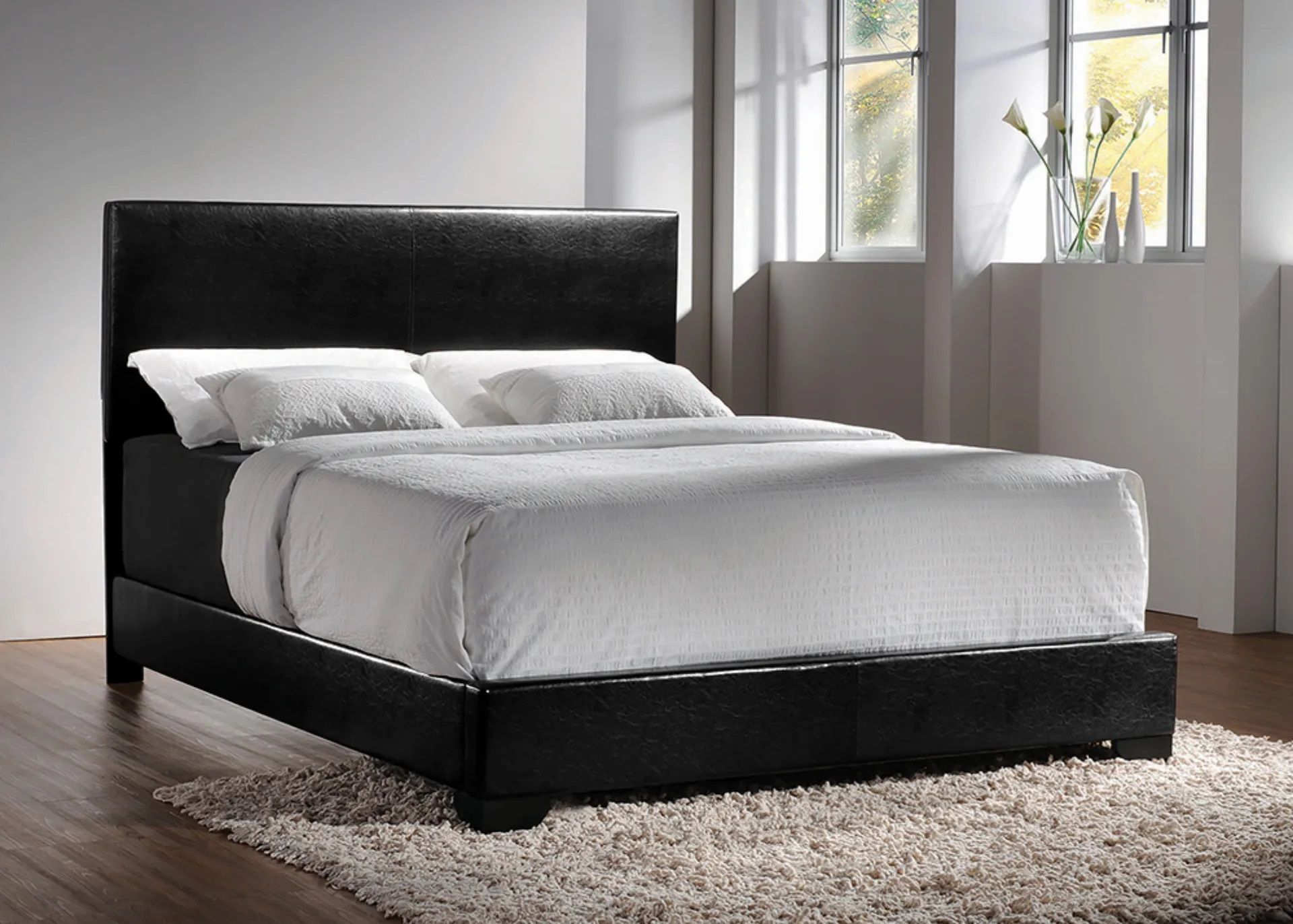A bed with a black headboard and white sheets