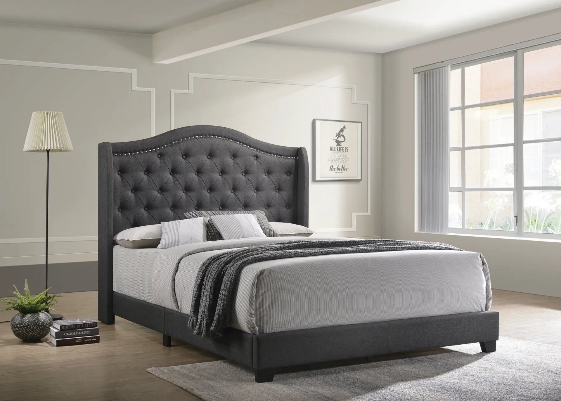A bed with a tufted headboard is sitting in a bedroom next to a window.