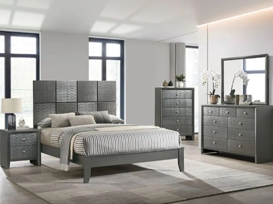 A bedroom with a bed , dresser , nightstand and mirror.