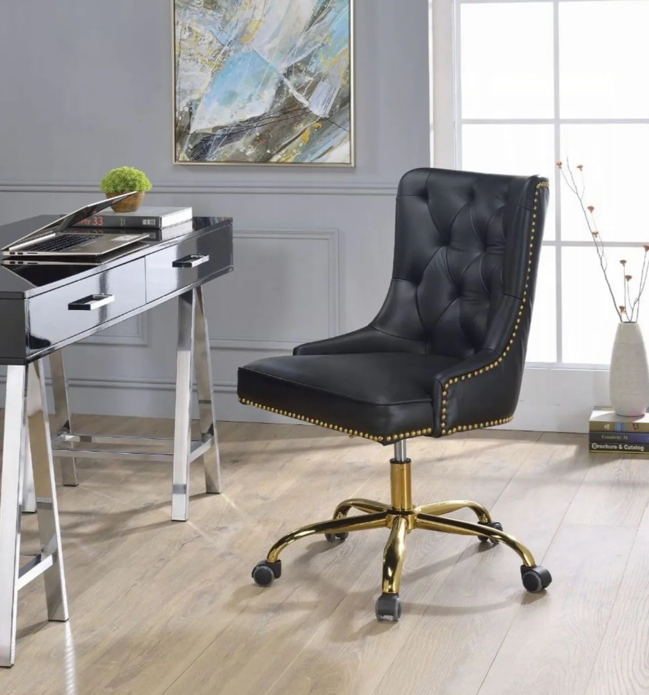 A black chair is sitting in front of a desk in a room.