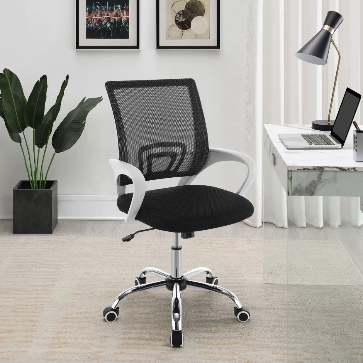 A black office chair is sitting in front of a desk with a laptop on it.