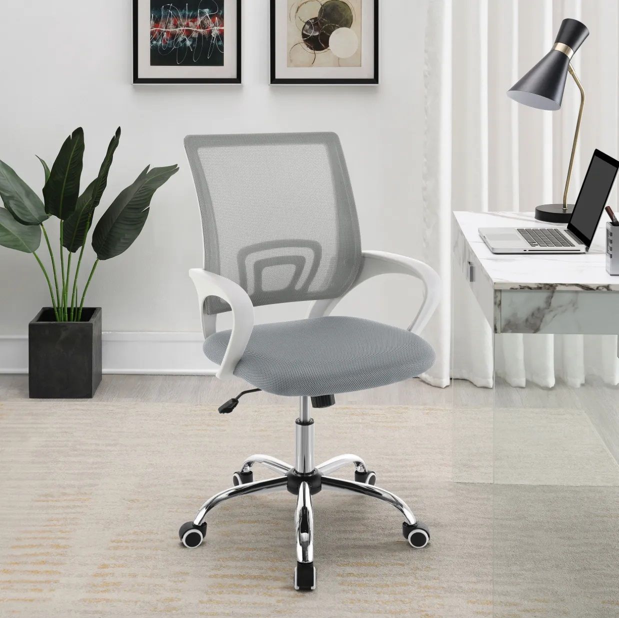 A gray office chair is sitting in front of a desk with a laptop on it.
