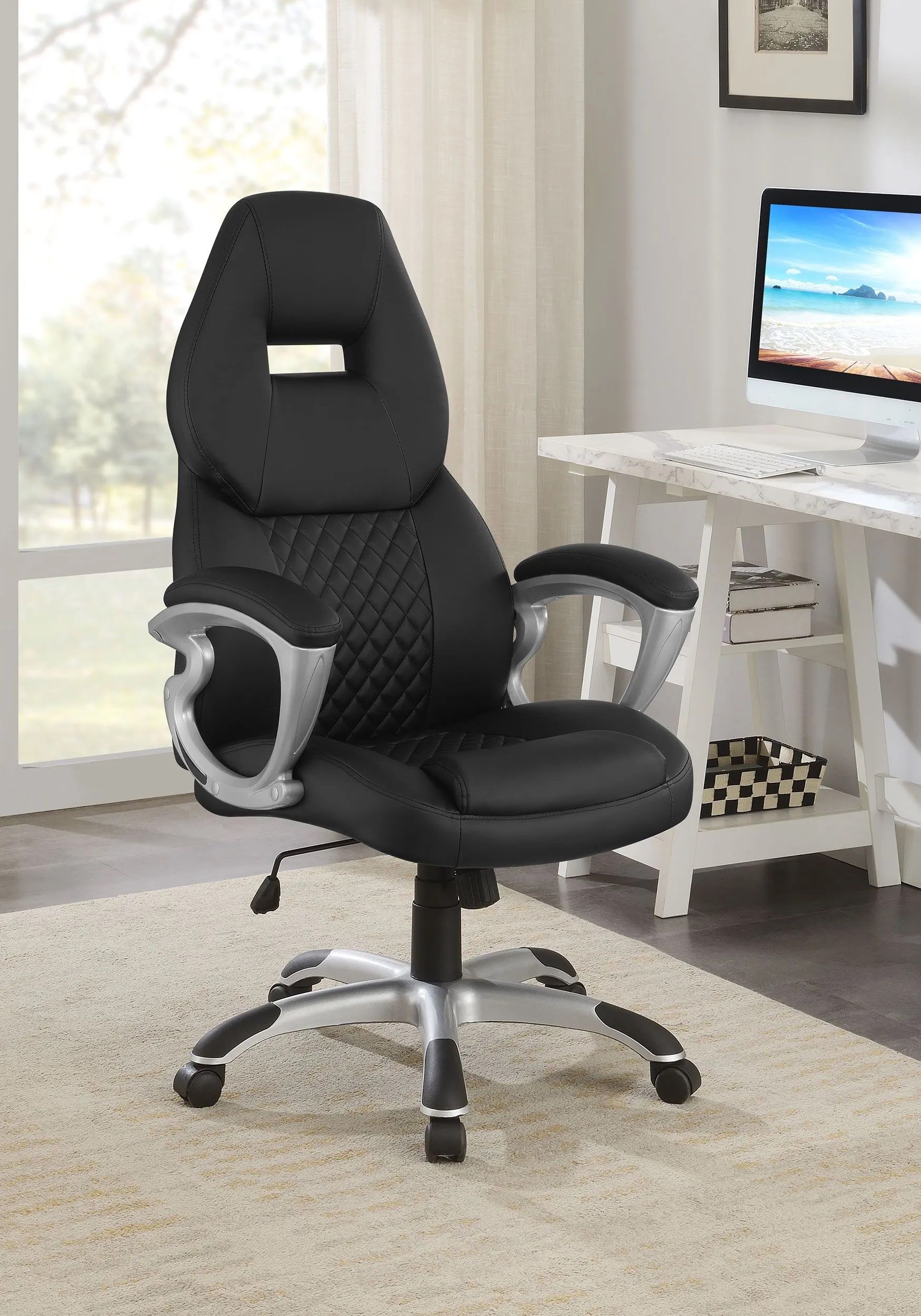 A black office chair is sitting in front of a computer desk in a room.
