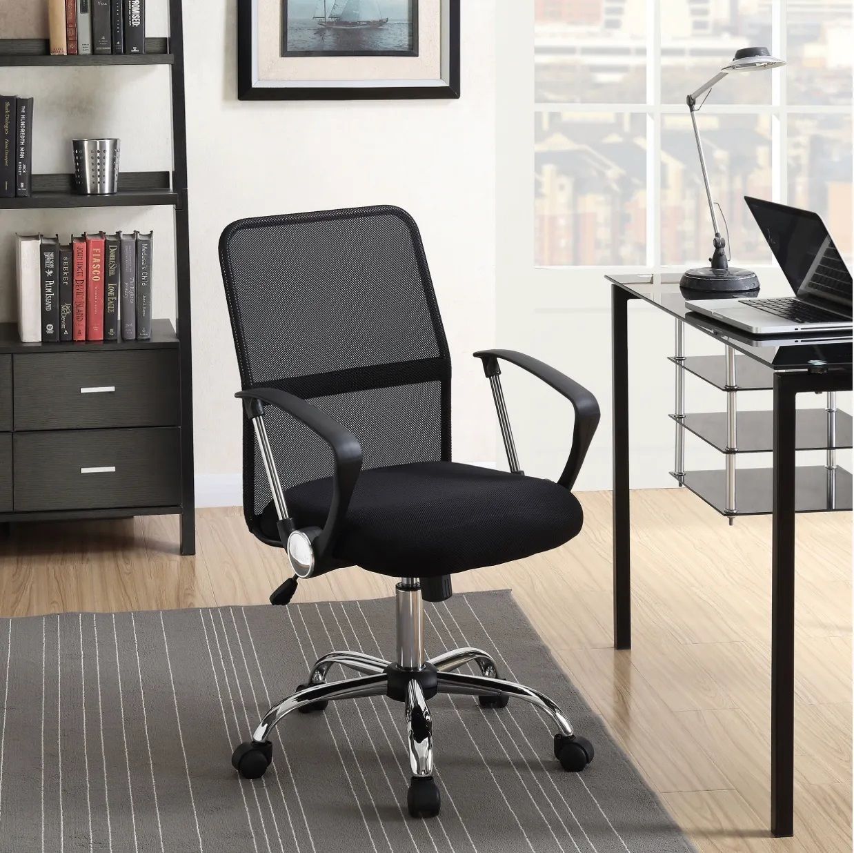 A black office chair sits in front of a desk with a laptop on it