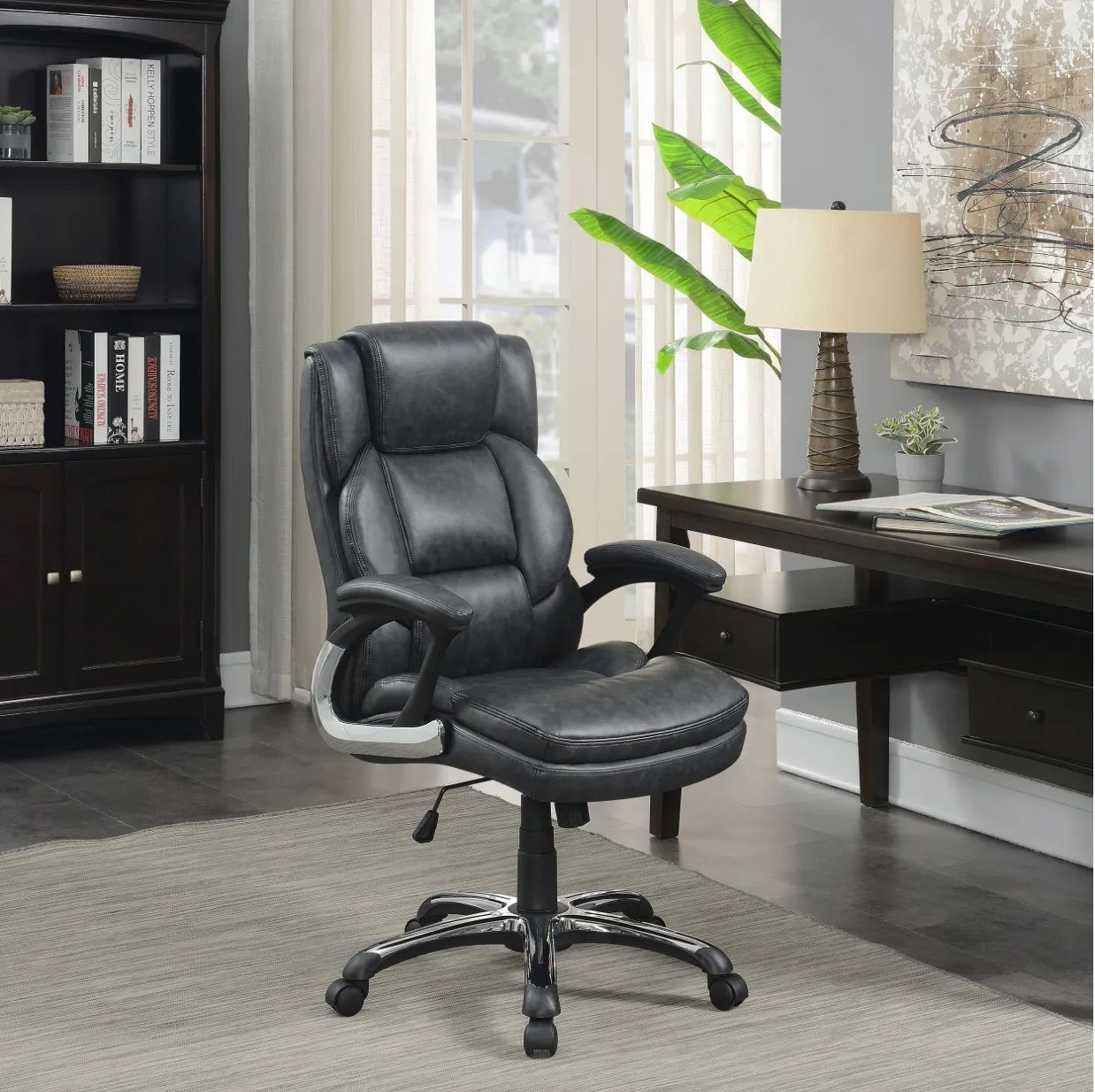 A black leather office chair is in a living room next to a desk