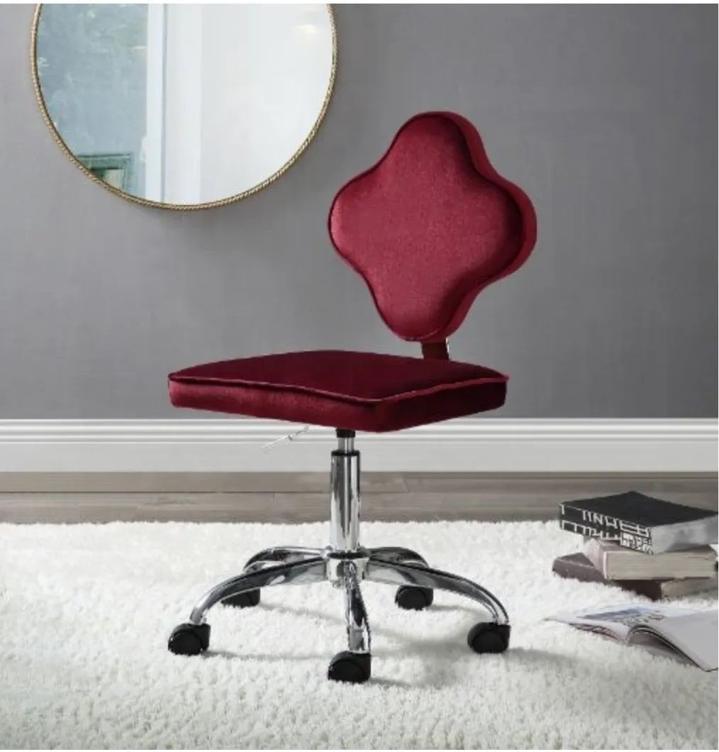 A red chair is sitting on a white rug in front of a mirror