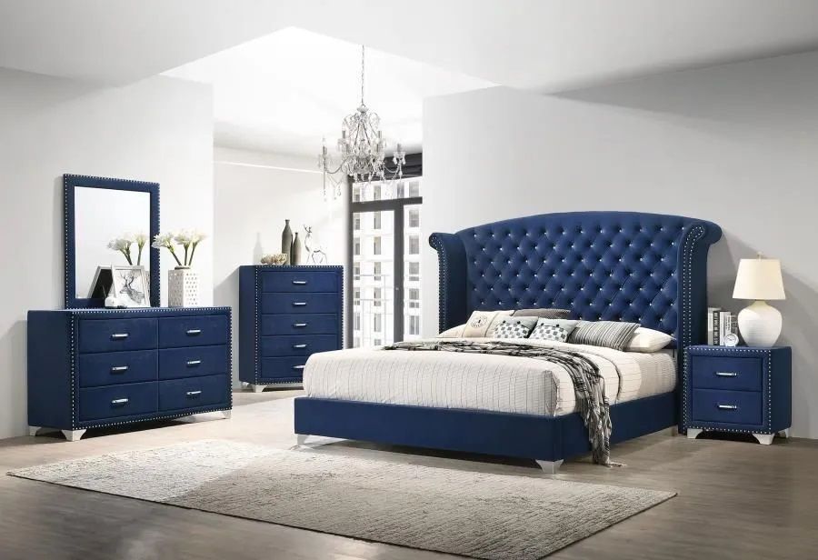 A bedroom with a blue bed , dresser , nightstand and mirror.