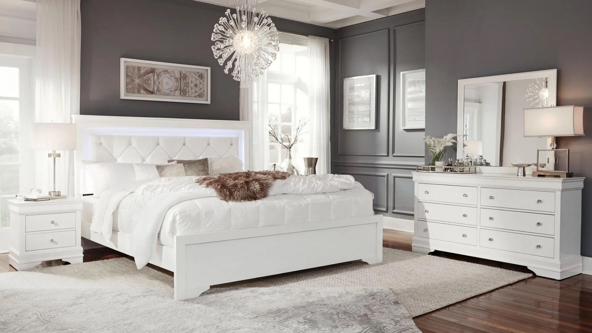 A bedroom with a bed , dresser , nightstand and mirror.
