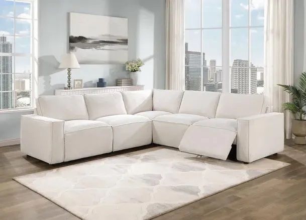 A white sectional couch is sitting on top of a white rug in a living room.