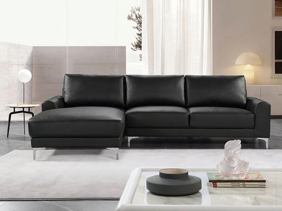 A living room with a black leather couch and a white coffee table