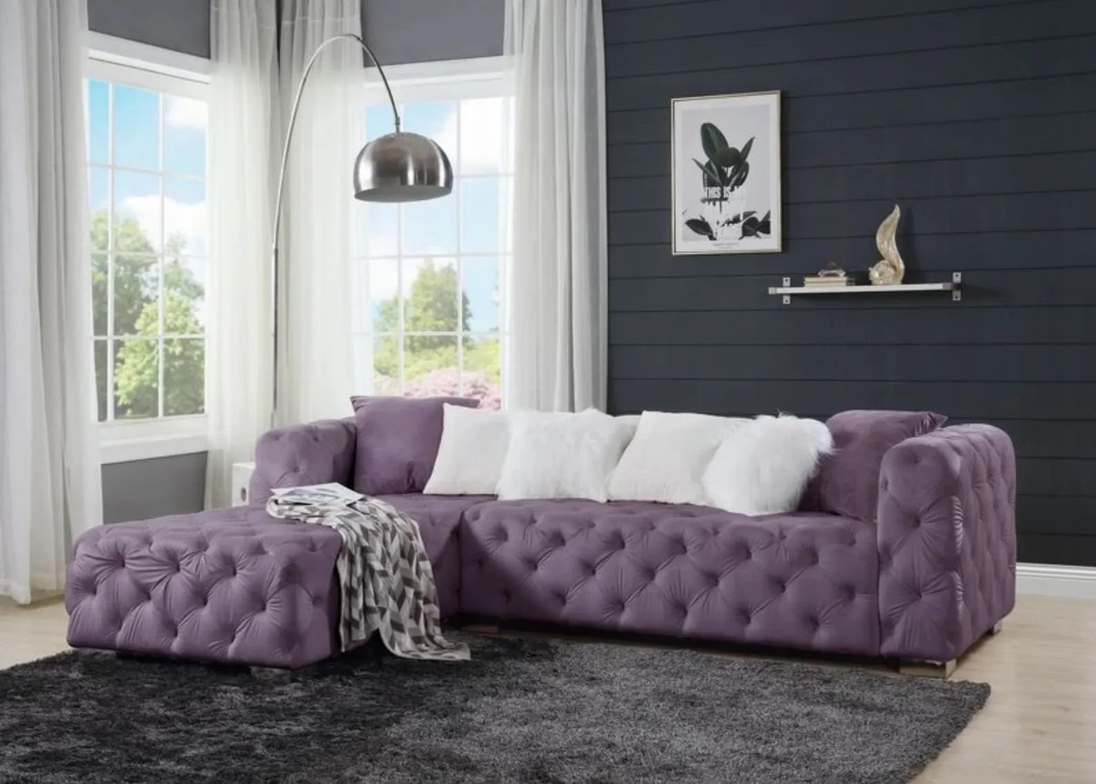 A living room with a purple sectional couch and ottoman.