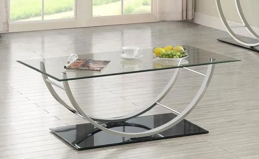 A glass coffee table with a bowl of fruit on it in a living room.