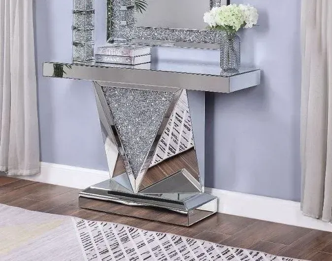 A mirrored console table with a vase of flowers on top of it in a living room.