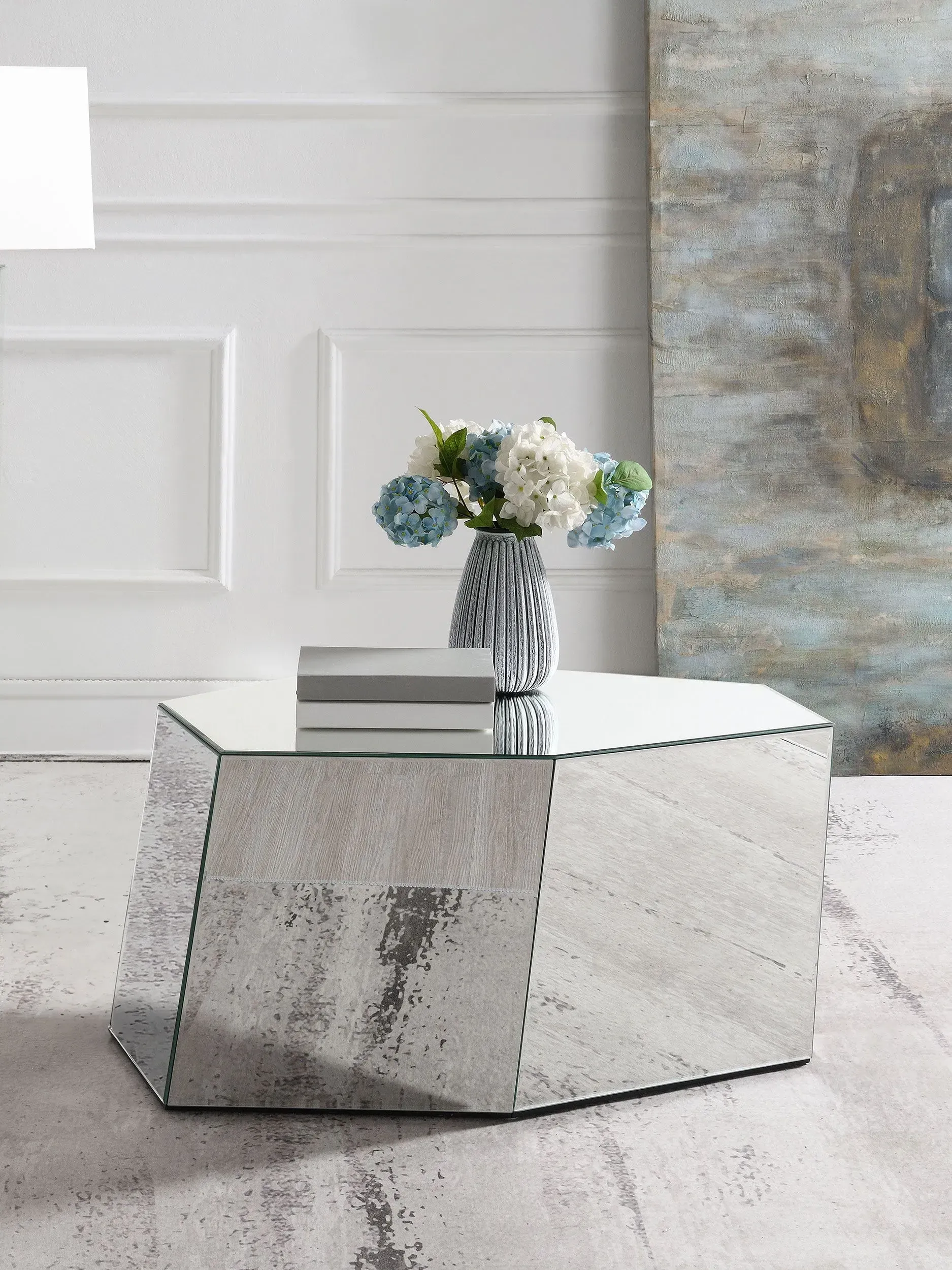 A mirrored coffee table with a vase of flowers on it.