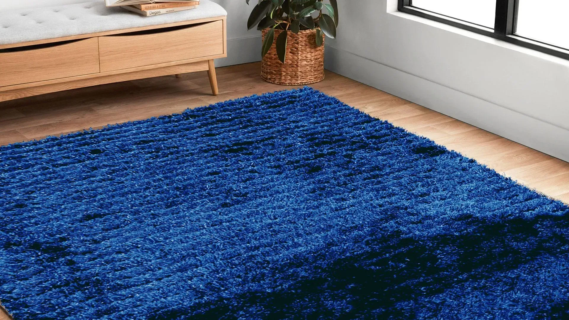 A blue rug is sitting on a wooden floor in a living room next to a window.