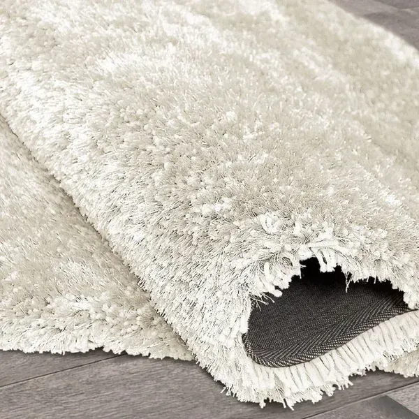 A white rug is laying on a wooden floor.