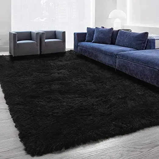 A living room with a couch , chairs , and a black rug.