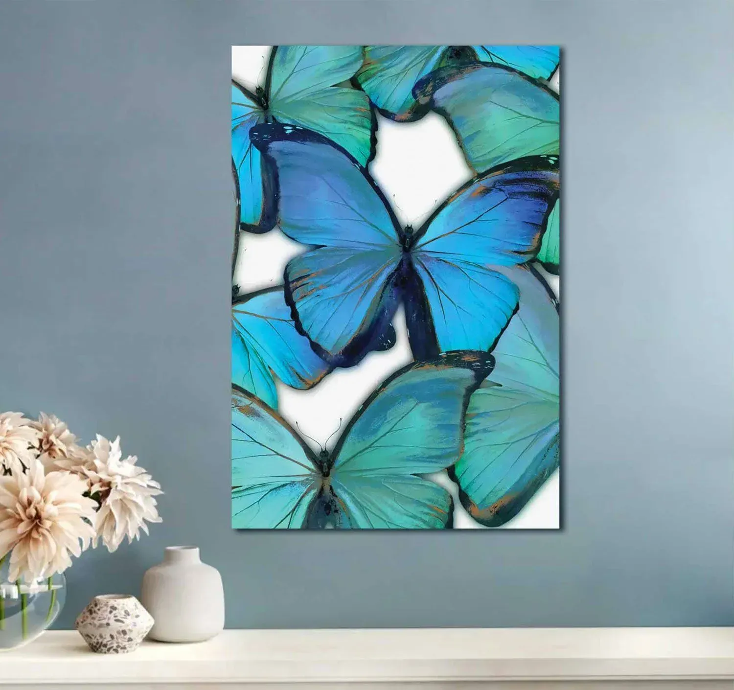 A painting of blue butterflies on a white background is hanging on a wall.
