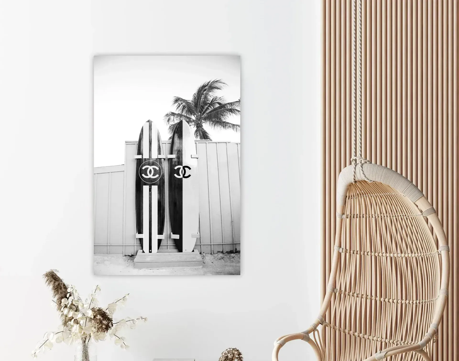 A black and white photo of two surfboards hanging on a wall next to a wicker chair.