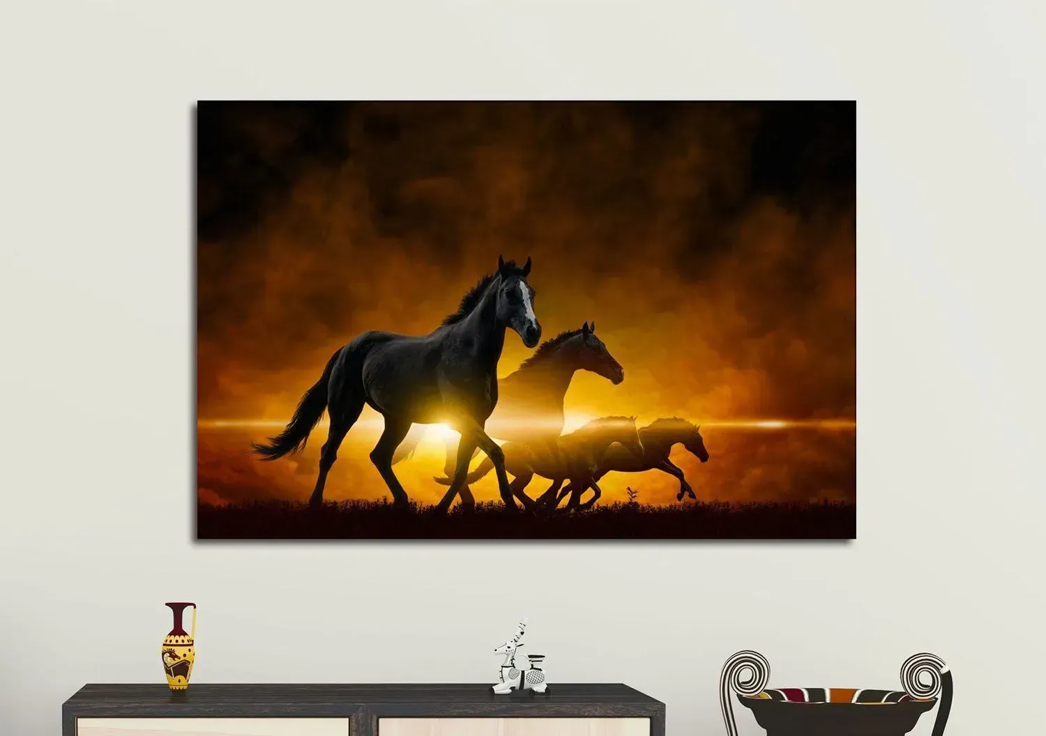 A group of horses are running in a field at sunset.