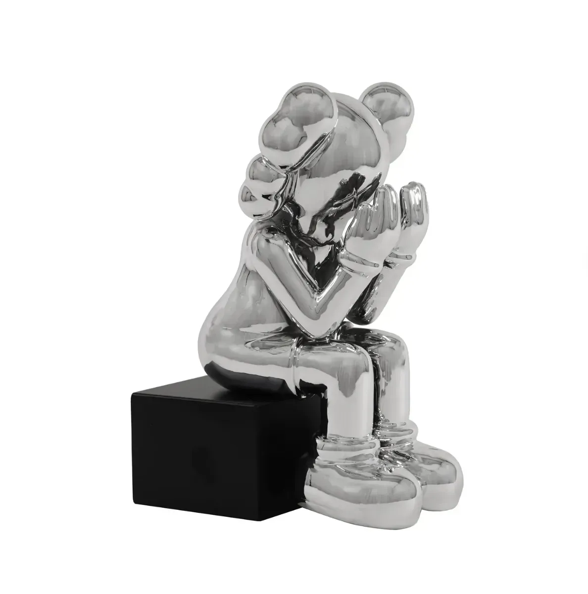 A silver statue of a person sitting on a black box