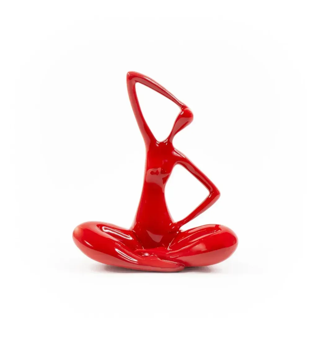 A red statue of a person sitting in a lotus position