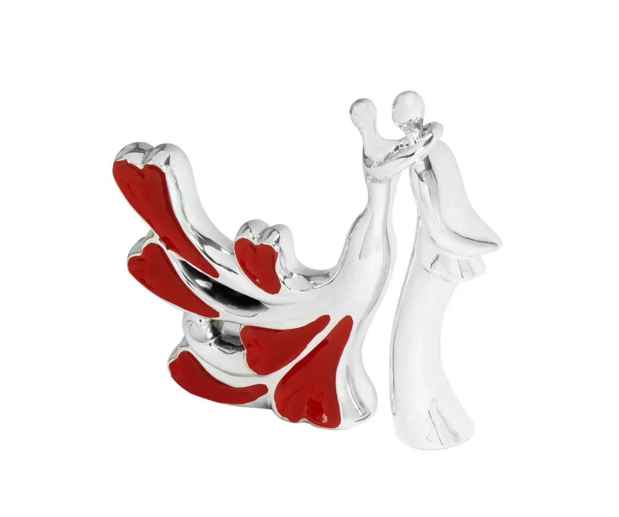 A statue of a bride and groom with red hearts on them