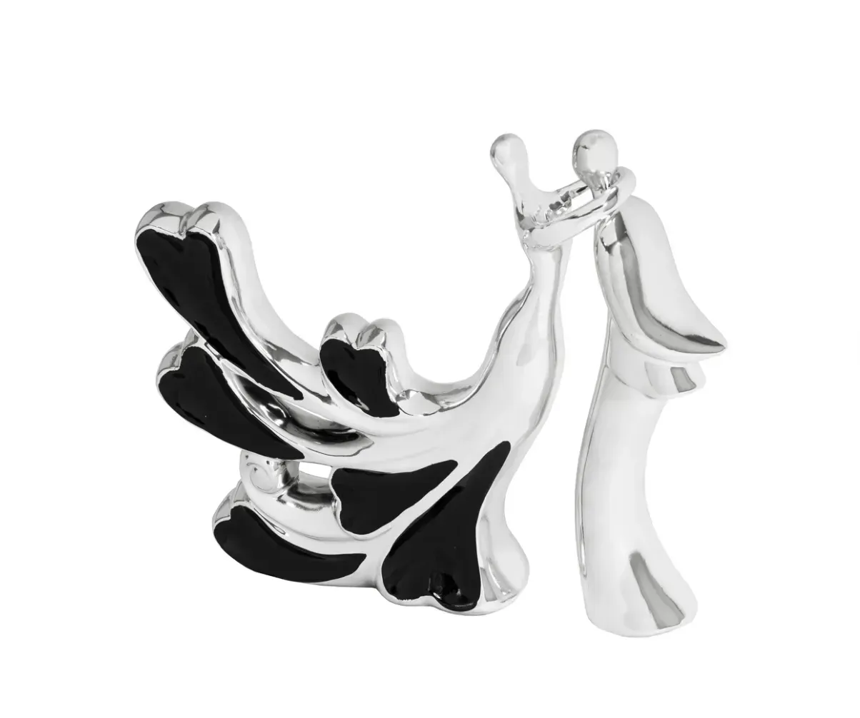A silver and black figurine of a bride and groom kissing